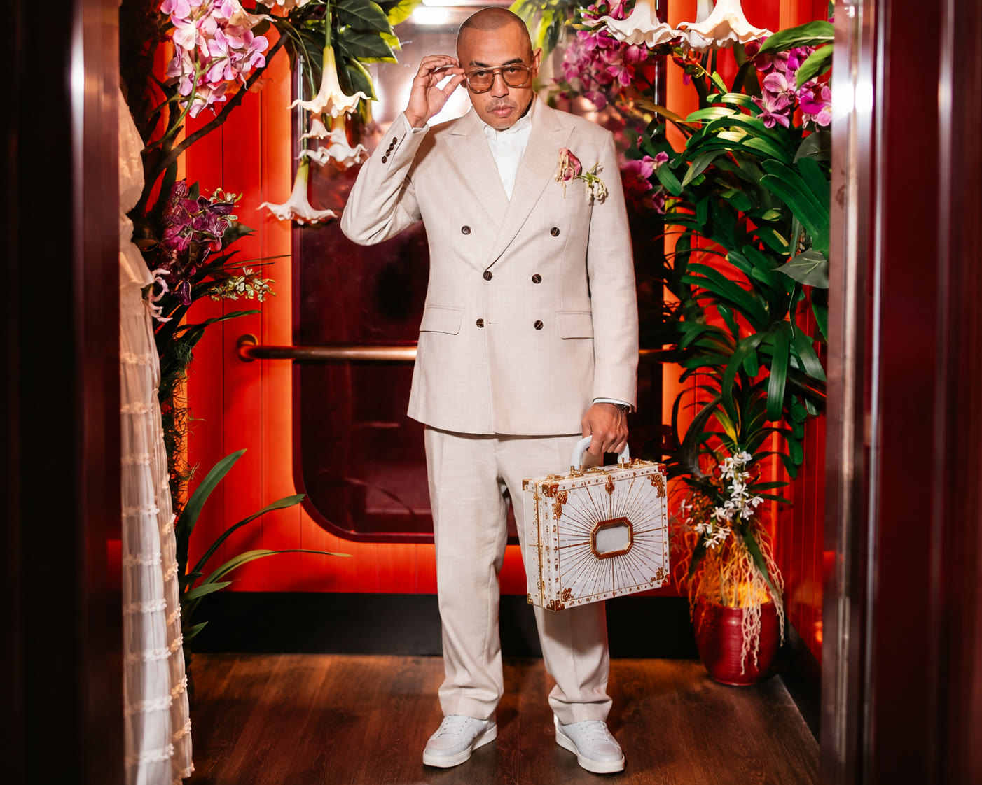Joe Flizzow in a cream suit, white and gold case, red interior with orchids