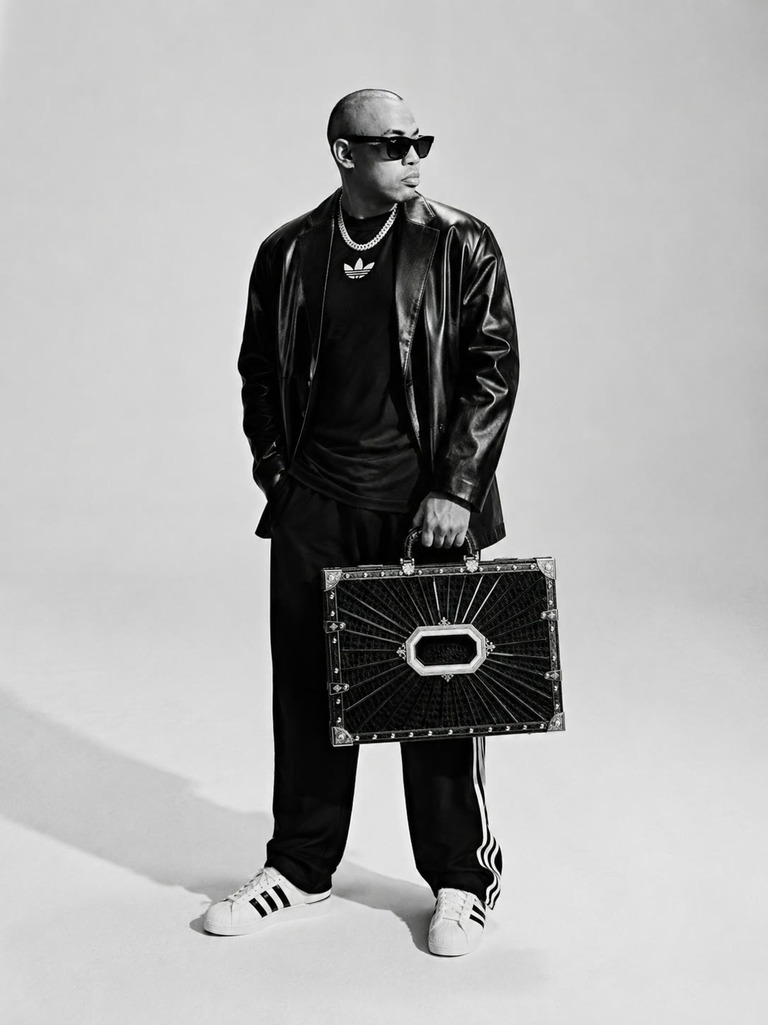 Joe Flizzow in a leather jacket holding the black case, black and white