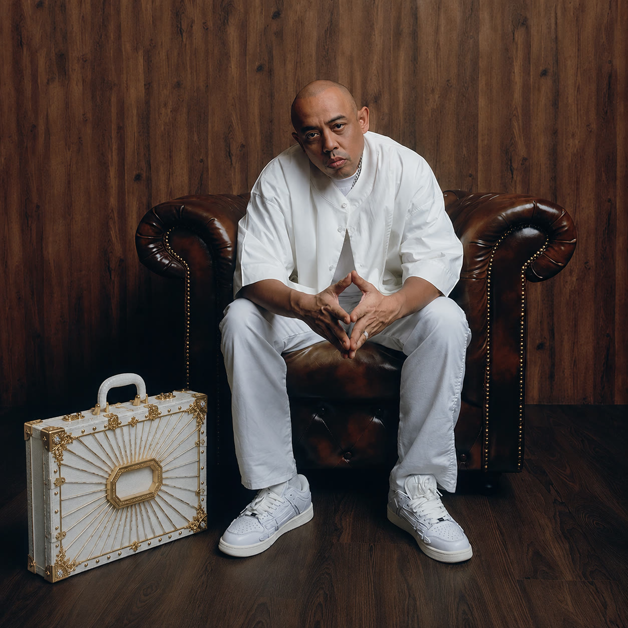 Joe Flizzow seated in white, case on the floor beside him